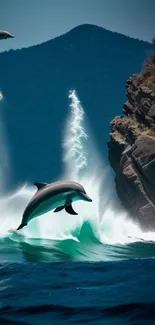 Dolphins leaping in front of a rocky cliff with ocean waves.