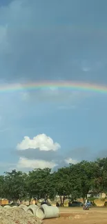 Double rainbow over a peaceful countryside landscape with blue sky.