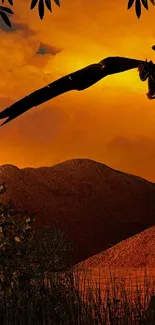 Silhouette of a dragon against an orange sunset sky over mountains.