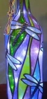 Stained glass bottle with dragonflies in blue and green hues.