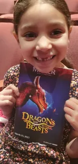 Child holding Dragons and Mythical Beasts poster in a theater.