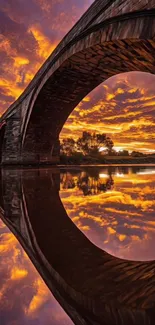 Sunset through bridge arch reflected on water.