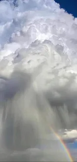 High contrast image of dramatic clouds with a rainbow against a vibrant blue sky.