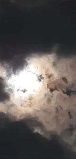 Dark clouds surrounding a bright moon in a night sky.