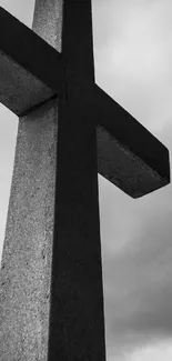 Black and white cross silhouette against cloudy sky.