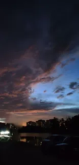 Dramatic evening sky with clouds and a silhouetted landscape.