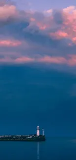 Lighthouse under colorful sunset clouds over calm sea.