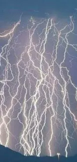 Dramatic lightning strikes over a mountain silhouette at night.