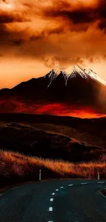 Road leading to snow-capped mountain under a dramatic orange sunset sky.