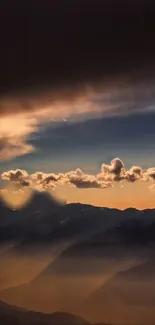 Dramatic sunset over mountains with glowing clouds and dark blue sky.