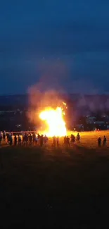 Bonfire illuminating the night with people gathered around.