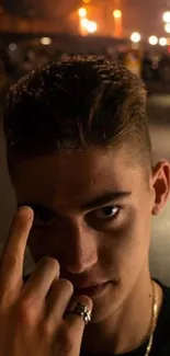 Moody portrait of a young man at night with street lights in the background.