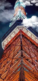 Illuminated tower against a dramatic cloudy night sky, showcasing architectural beauty.