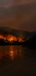 Nighttime scene of forest fire reflecting on a river under a dark sky.