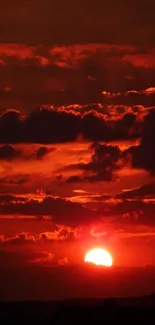 Dramatic sunset with dark red clouds and glowing sun.