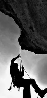 Silhouette of a climber on a rock face in black and white.