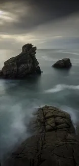 Dramatic seascape with rock formations and swirling ocean waves under a moody sky.