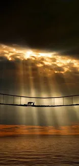 Bridge with golden sunset and dramatic clouds over ocean.