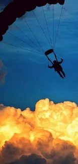 Silhouette of a parachutist against a vibrant orange clouded sky.