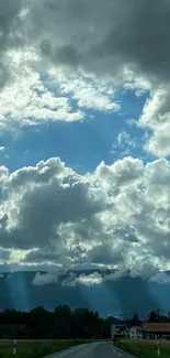 Mobile wallpaper of a cloudy sky with sunlight over a rural road.