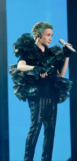 Artist in dramatic black outfit performing on stage.