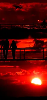 Silhouette art of people at sunset with vibrant red sky.