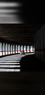 Car driving through shadowed urban tunnel with artistic light play.