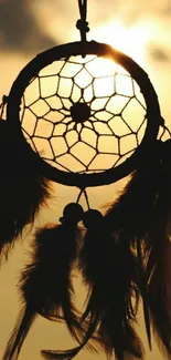 Silhouette of a dreamcatcher against a sunset sky.