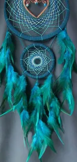 Dreamcatcher with teal feathers on dark background.