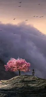 Cherry blossom tree atop rocky hill under dreamy sky.