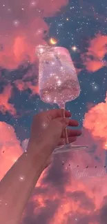 Hand with a starry glass against pink clouds and starry night sky.