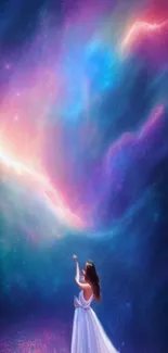 A woman in white reaches for the vibrant, colorful galaxy night sky.