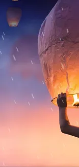 A child launches a glowing lantern into a colorful twilight sky.