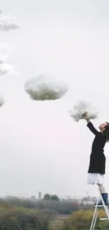 Person on ladder reaching clouds in countryside.