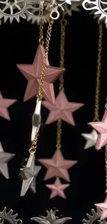 Mobile wallpaper with pink stars and gears hanging on chains.