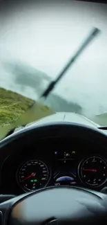 Driving through misty mountain scenery with rain and clouds.