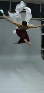 Dancer in dynamic pose mid-air on a studio backdrop.