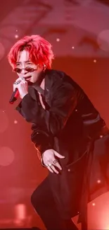 Artist with red hair performing dynamically on stage under red lighting.