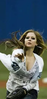 Woman throwing baseball with intensity on field, blue background.