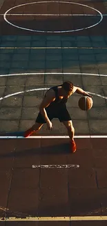 A basketball player dribbles on a sunlit urban court.