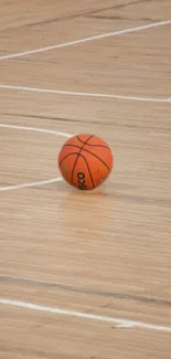 Orange basketball on brown court with white lines.