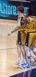 Basketball players in yellow jerseys embrace on court.