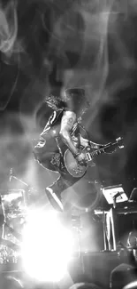 Guitarist jumps on stage in dramatic black and white shot.