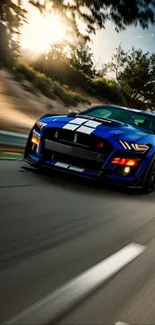 Blue sports car speeding on a scenic road at sunset.