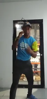 Person in boxing stance with blue shirt indoors.