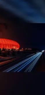 Dynamic city nightscape with stadium glow and car light trails.