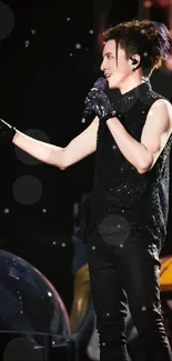 Energetic concert performer in dynamic stage pose with black outfit and gloves.