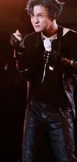 Energetic performer with blue hair in concert, wearing black leather, holding a mic.