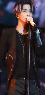 Singer in black performing on stage with vibrant lighting in the background.