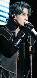 Performer on stage with microphone in dark attire.